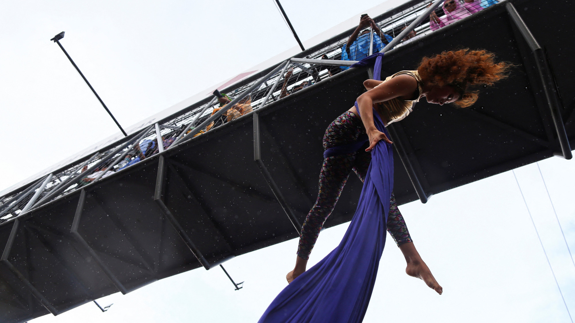A woman hangs from a bridge