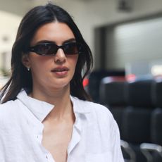a close up of Kendall Jenner wearing a white button down shirt with sunglasses