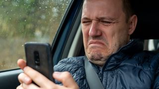 A man looks at his phone in anguish