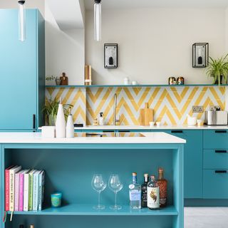 Turquoise kitchen with white worktops and yellow geo patterned splashback