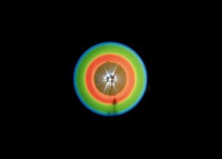 This pattern is created when scientists send a laser beam through a crystal, occasionally producing a connected pair of twin photons. These photons will always be separated from each other by 180 degrees around the circle.