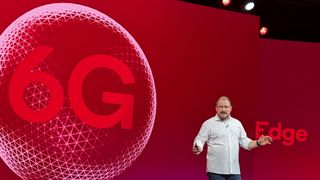 Qualcomm CEO Cristiano Amon on stage with 6G graphic concept behind him