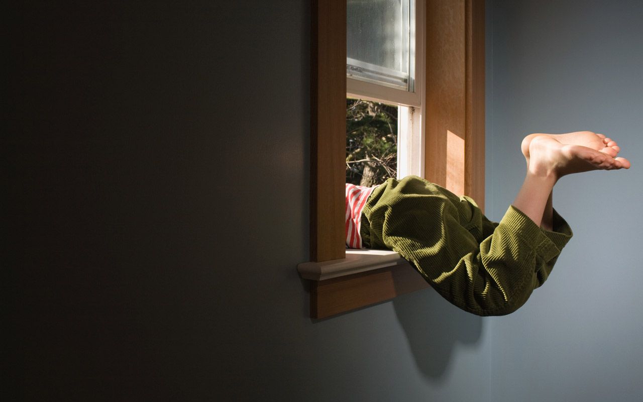 An image of someone climbing out a window with their feet still in the house