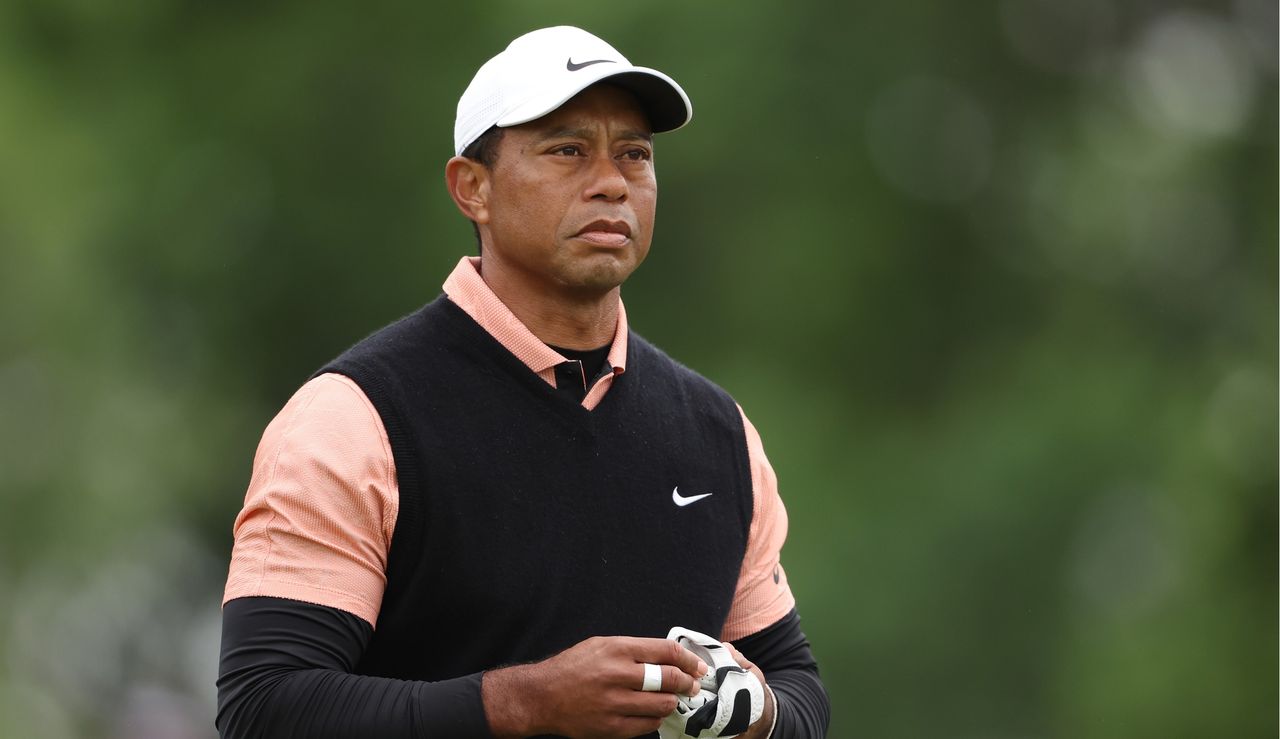 Woods removes his glove whilst watching a tee shot