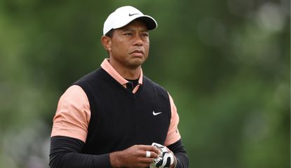 Woods removes his glove whilst watching a tee shot