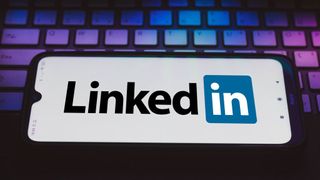 The LinkedIn logo displayed on a smartphone resting on a keyboard