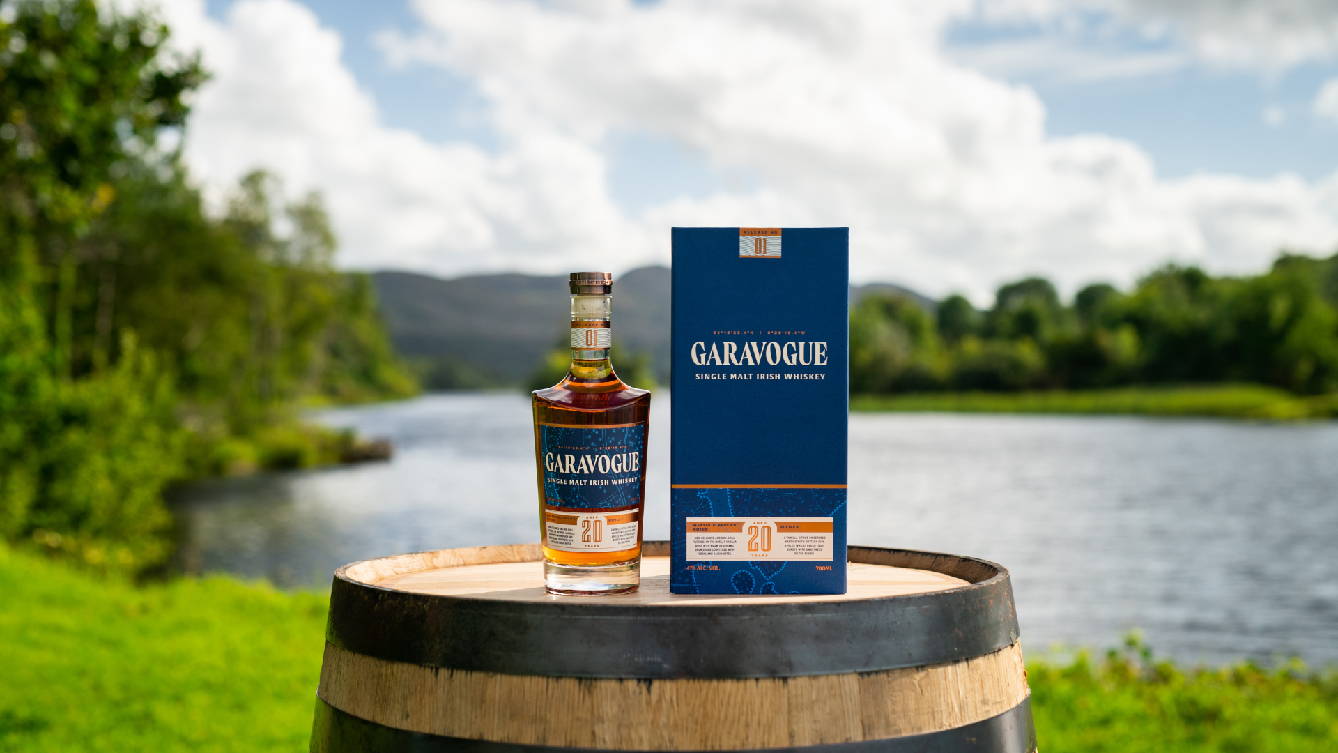 an image of Garavogue whiskey bottle and box on top of a whiskey barrel outside in the grounds fo Hazelwood House overlooking the Garavogue River 