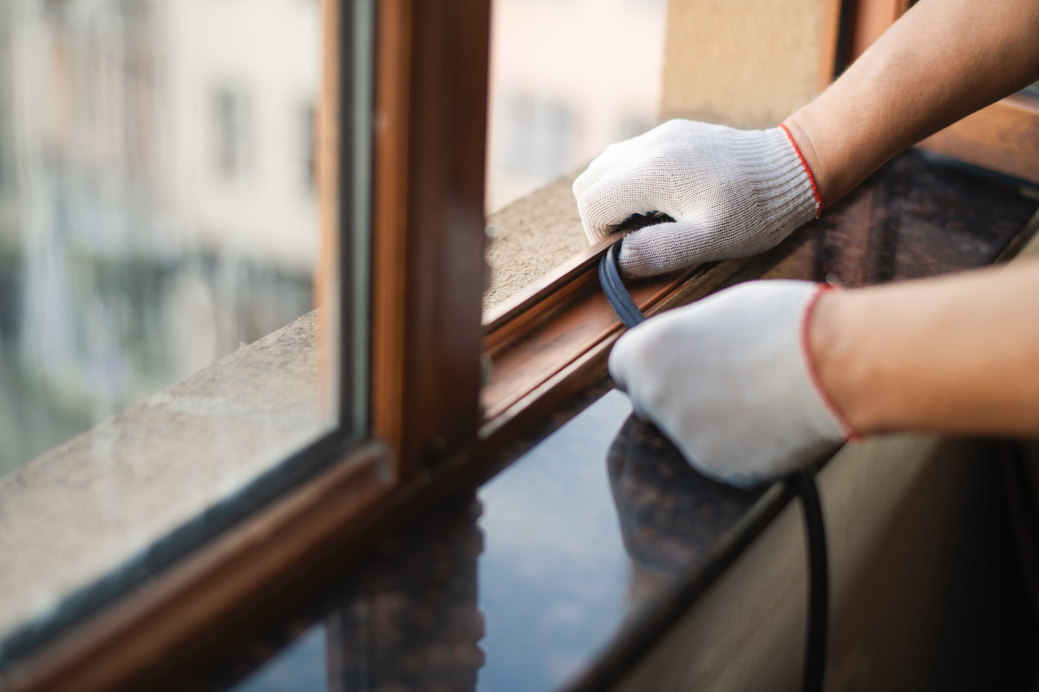 a person applies weatherstripping to their window frame