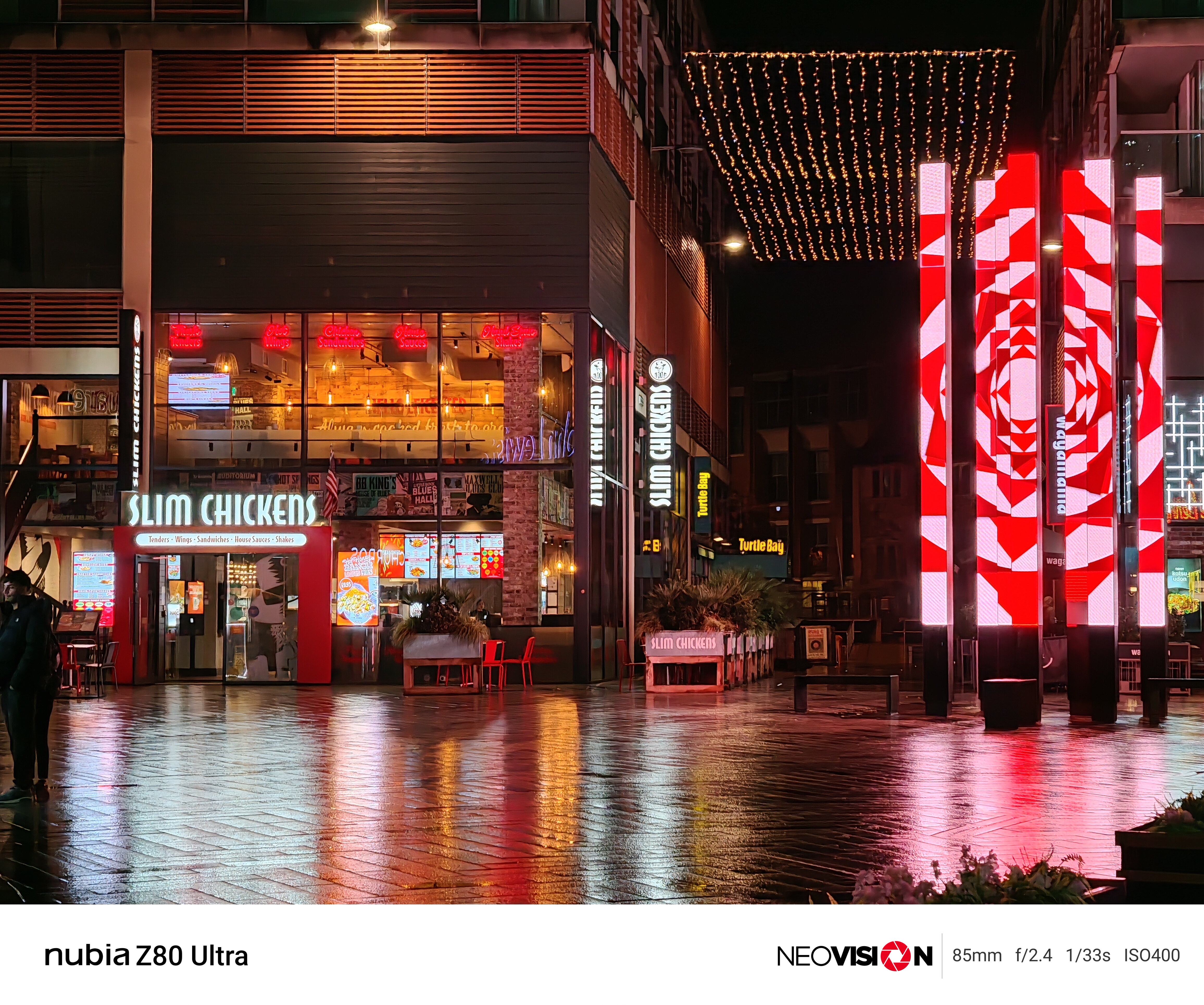 A shopping centre lit up at night with colorful lights