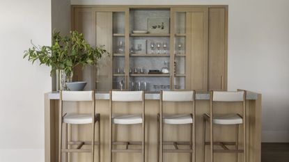 home bar with pale wood counter and stools with fitted cupboards