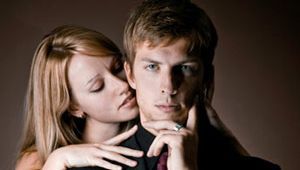 man in suit with woman behind him nuzzling his neck