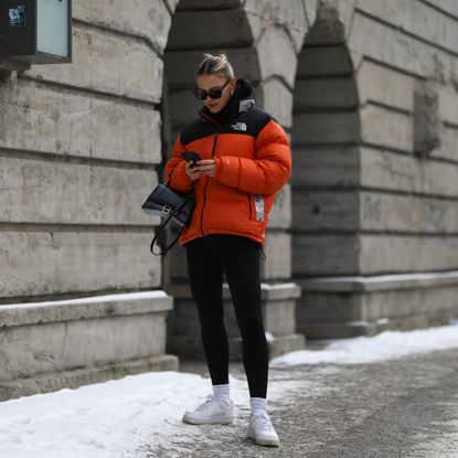 Alessa Winter wearing The North Face orange jacket, white Nike Air Force sneaker, Balenciaga black bag and black Ellesse leggings on February 15, 2021 in Berlin, Germany
