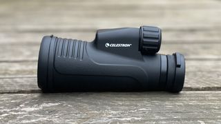 Celestron Outland X 10x50 monocular on a wooden surface