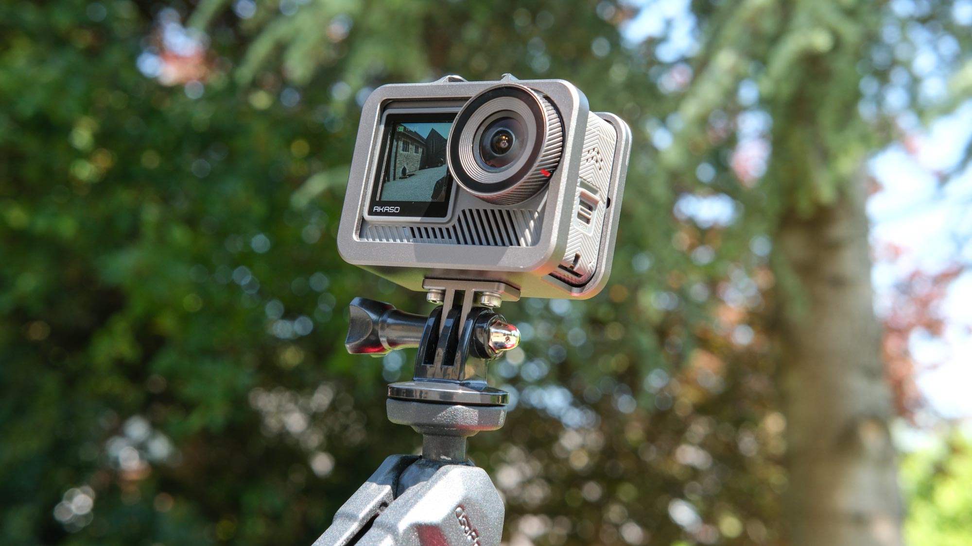 A photo of the Akaso Brave 8 Lite on a mount against a green, out of focus background.