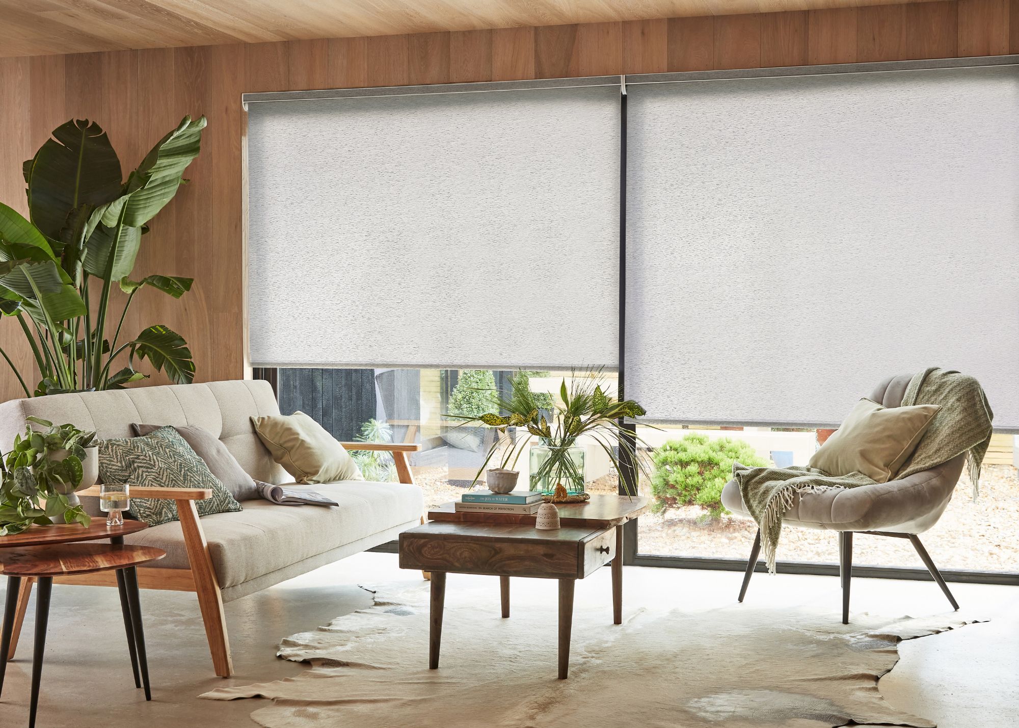 A modern living space with light gray roller blinds on sliding glass doors.