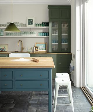 Green gray kitchen walls are a lovely background to this kitchen that features green cabinetry and a blue kitchen island