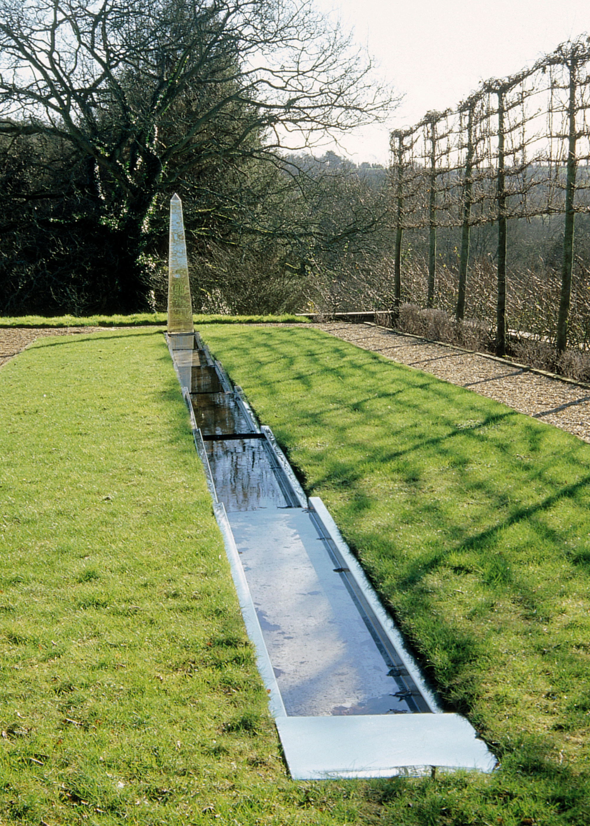 a small water rill in a green field with lots of trees scattered around