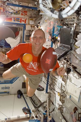 NASA astronaut Clay Anderson represents his birth state aboard the space station with a University of Nebraska football.