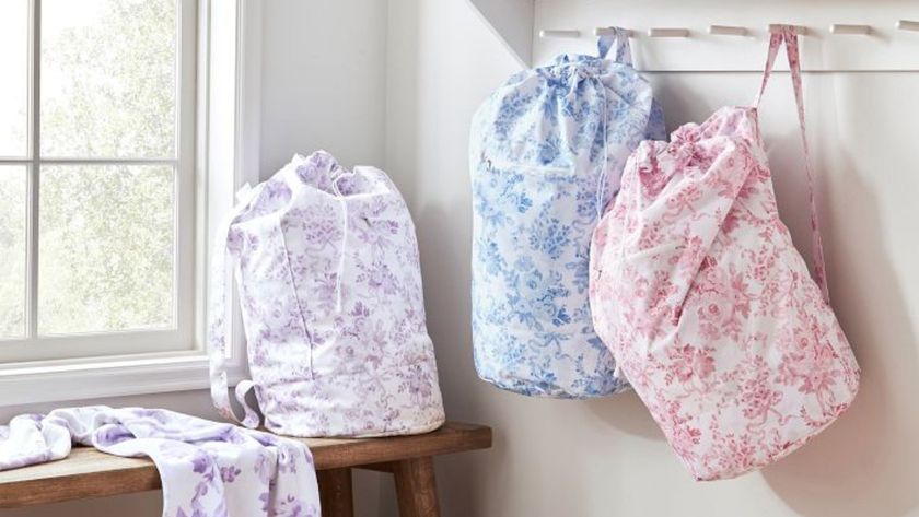 A white laundry room with three purple, blue, and pink floral laundry bags