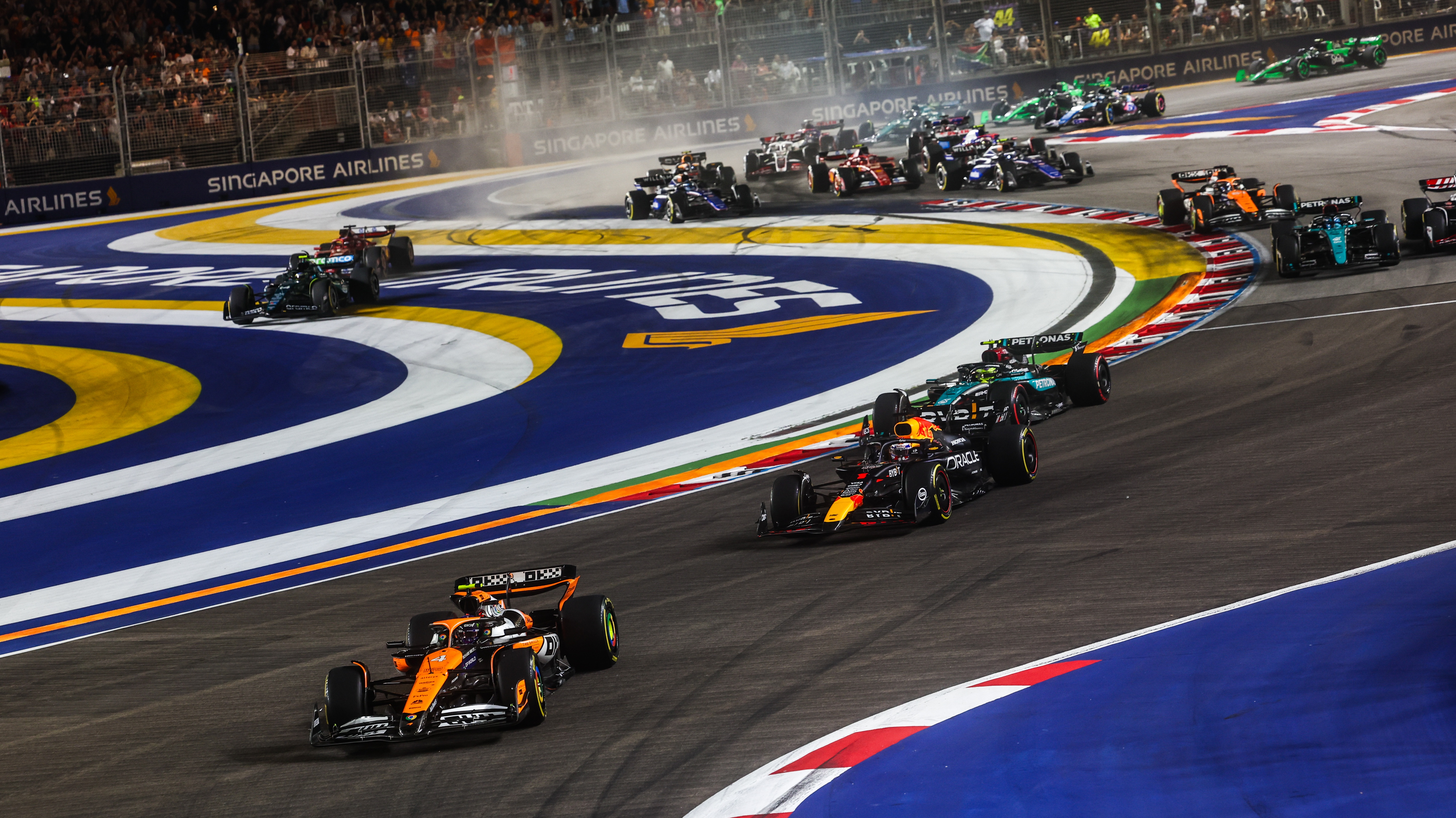 Lando Norris, McLaren MCL38, leads Sergio Perez, Red Bull Racing RB20, Sir Lewis Hamilton, Mercedes F1 W15, George Russell, Mercedes F1 W15, and the rest of the field as Fernando Alonso, Aston Martin AMR24, cuts on the opening lap during F1 Grand Prix Of Singapore at Marina Bay Street Circuit on September 22, 2024 in Singapore, Singapore. 