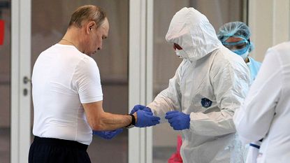 President Vladimir Putin putting on a personal protective suit ©