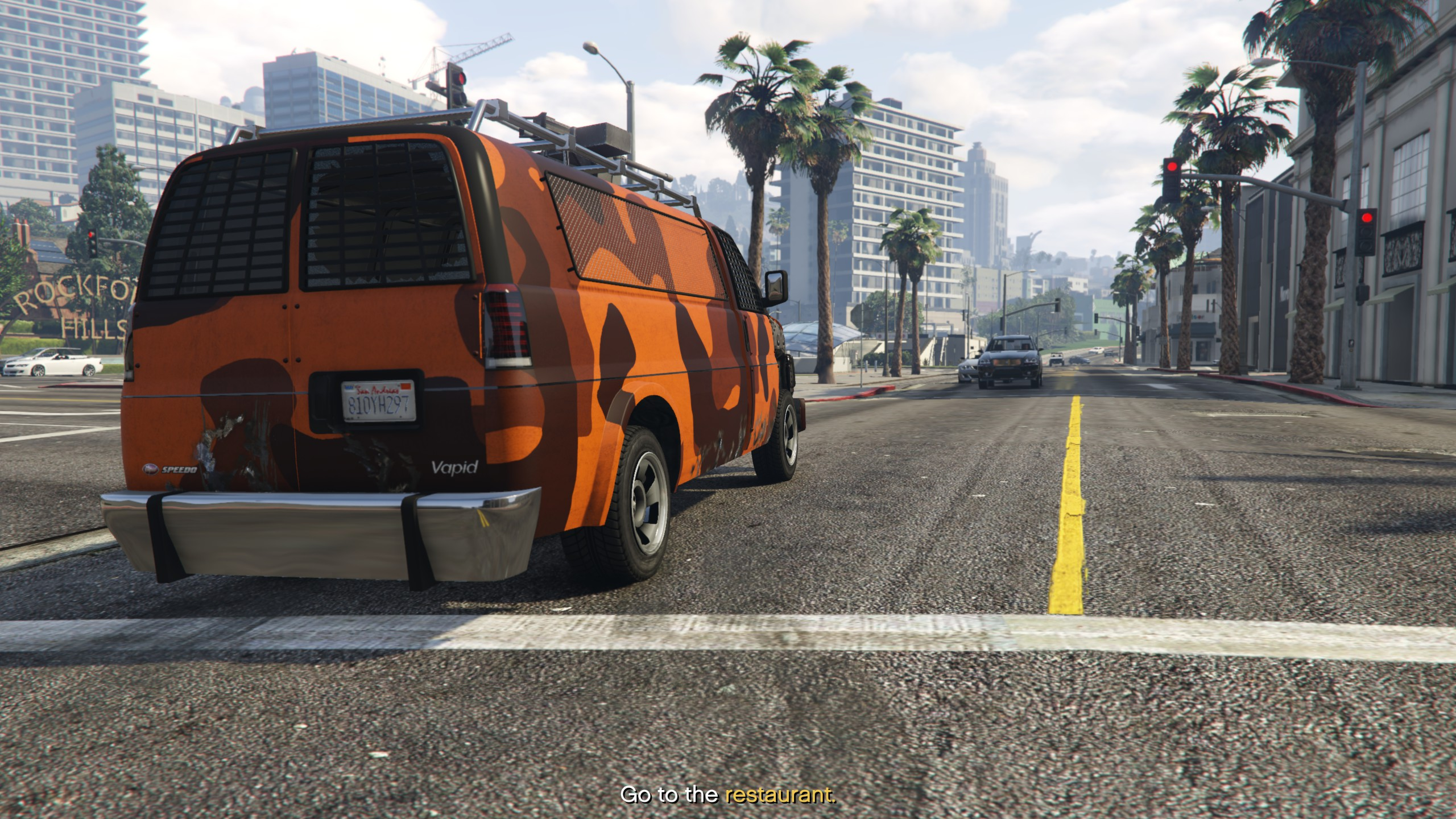 A van with orange camo drives down the road.