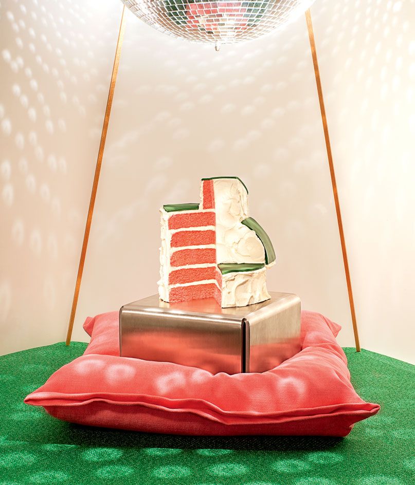 A cake slice, set on a metal pedestal, below a disco ball.