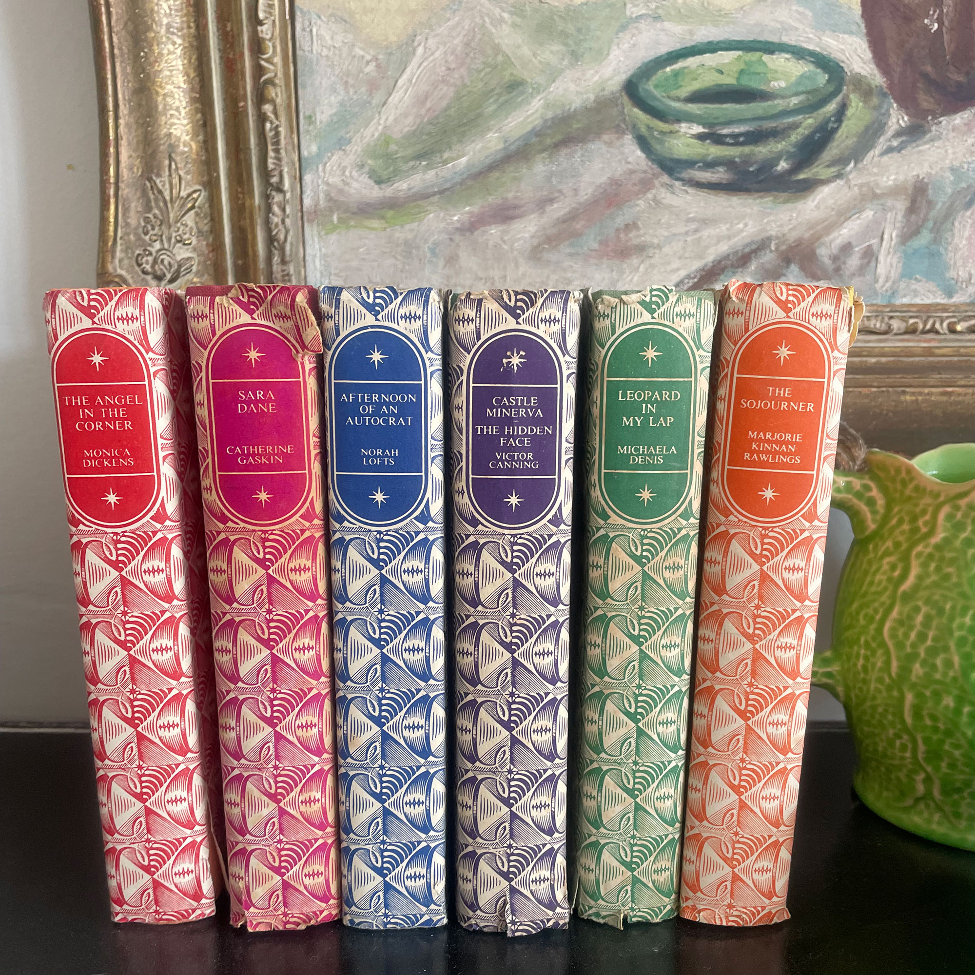 Row of colourful vintage books in front of painting