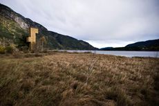 The Seljord watch tower infront of a body of water with mountains behind it