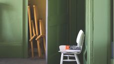 Chartreuse-painted storage room featuring folded furniture and a white mid-century-style chair