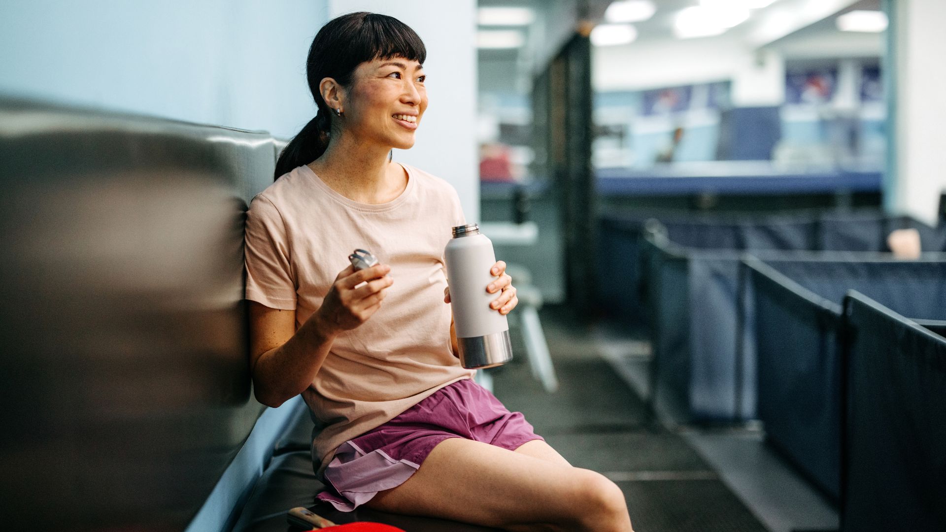 Woman drinking from water bottle at gym