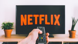 A remote control pointing at a TV displaying the Netflix logo