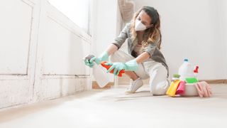 Woman cleaning dirty wall with cleaning products