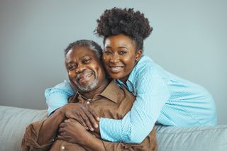 A smiling older father and daughter on the couch.