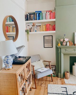 Living room with pastel green fireplace and bookshelves