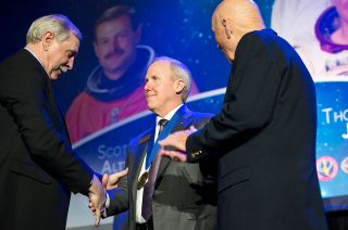 Astronauts Curt Brown (left) and Story Musgrave (right) welcome Thomas Jones into the U.S. Astronaut Hall of Fame at the Kennedy Space Center Visitor Complex on April 21, 2018.