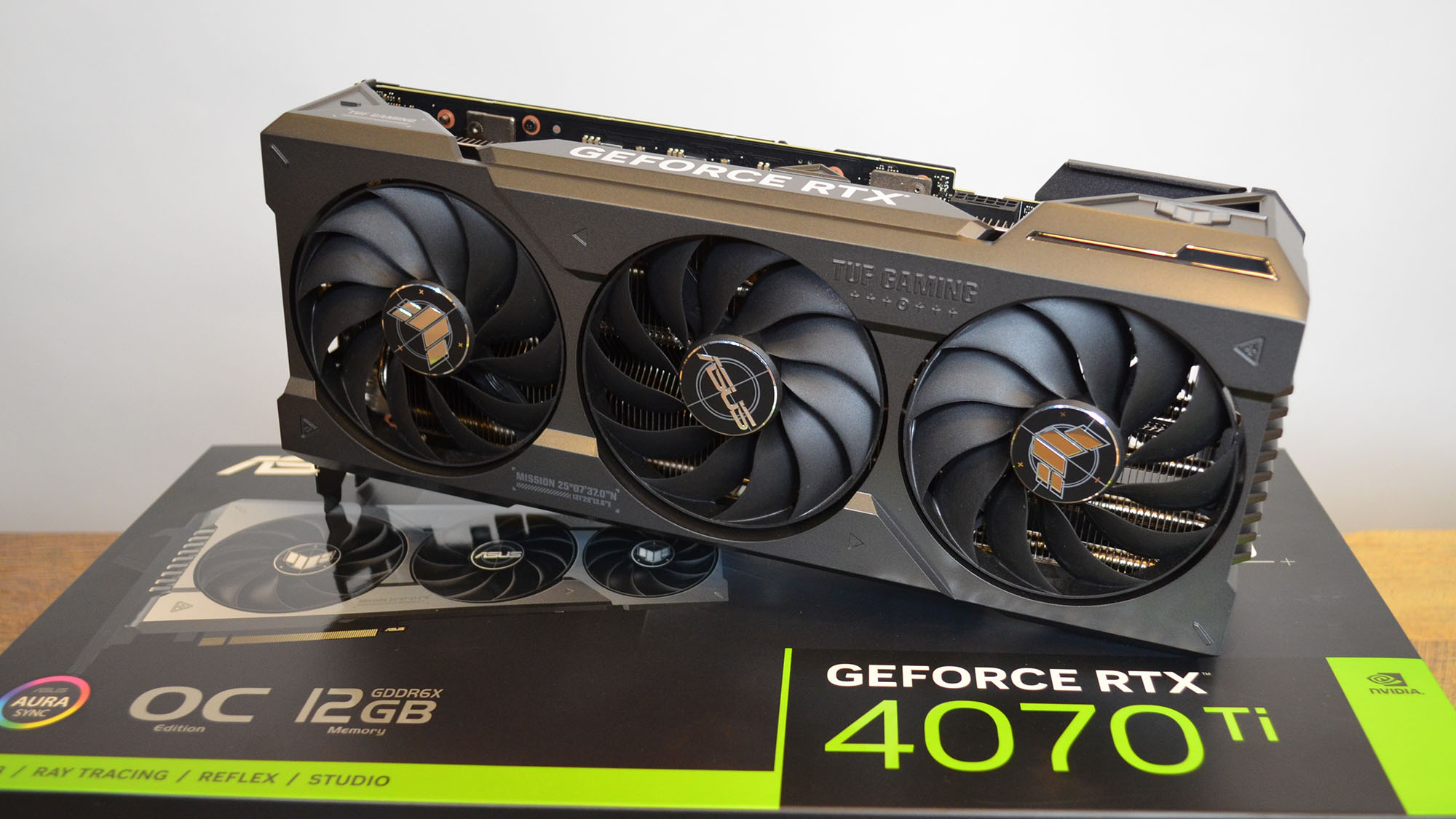 An Nvidia GeForce RTX 4070 Ti graphics card on a wooden table with its retail packaging