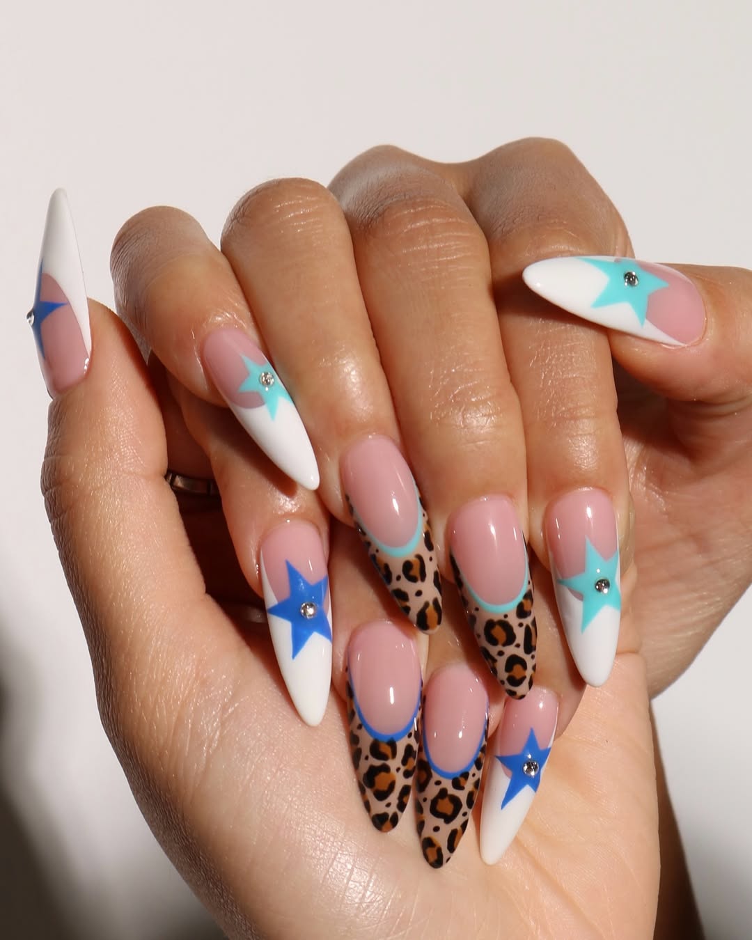 a person wearing a leopard french manicure with blue stars