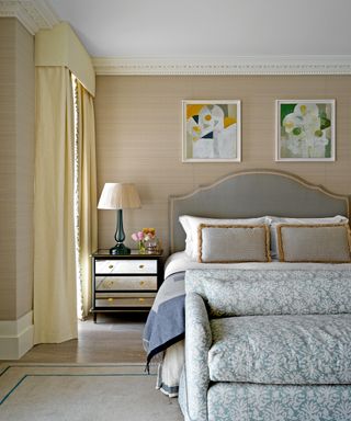 neutral bedroom with bed with gray headboard and pattered bed end sofa
