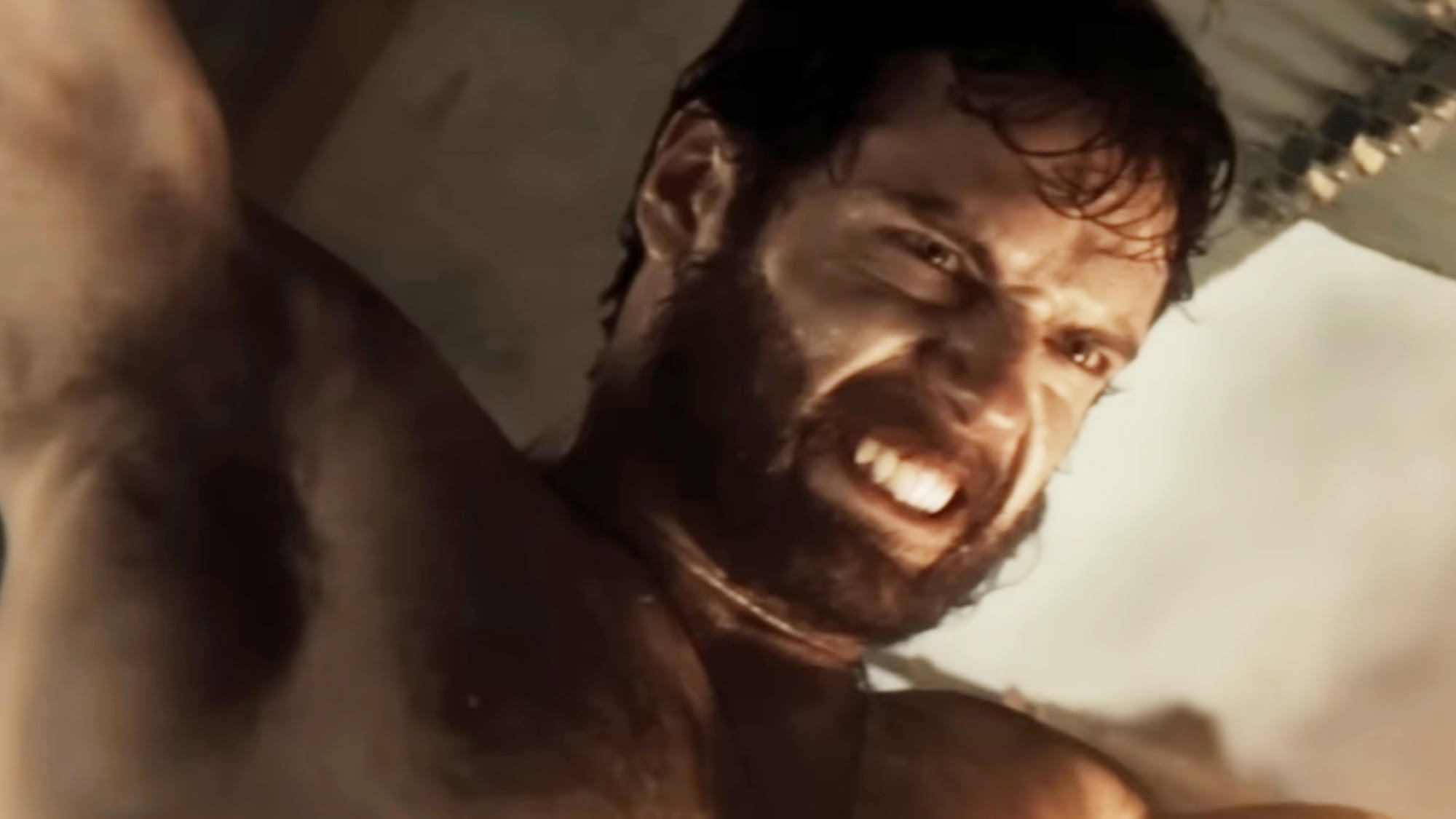 A bearded Henry Cavill lifting something heavy in Man of Steel