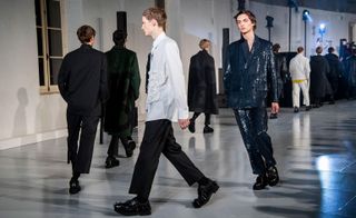 end of a long line of male models on a modeling runway