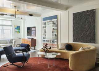 A living room with a curved champagne color sofa and a red area rug