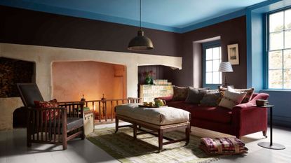 A traditional sitting room with an open fire. The walls are painted in brown and the ceiling in blue.