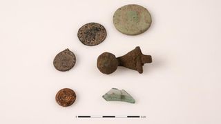 Small objects, including coins, a metal clasp and antique glass, found at the site.