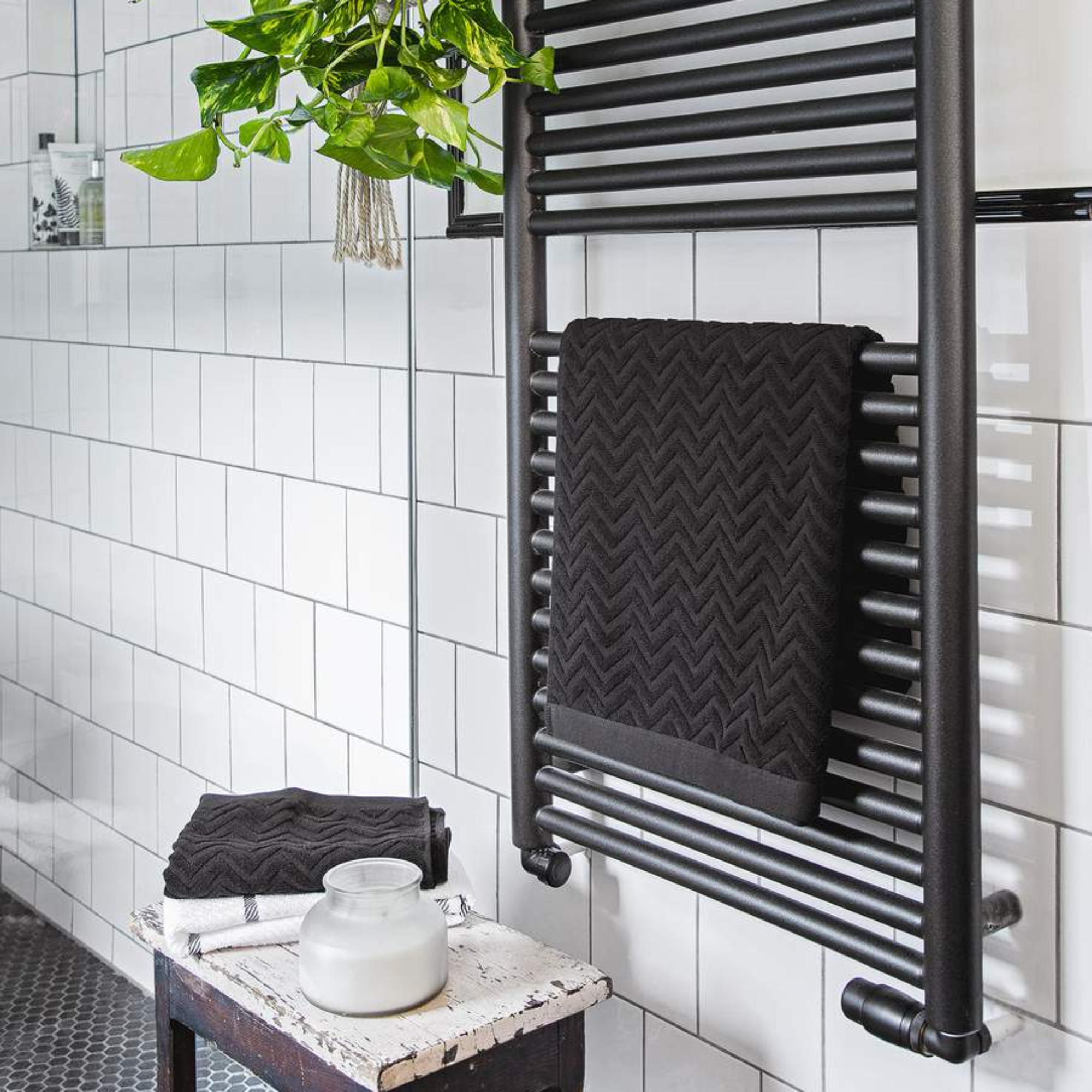 Close up of a black towel radiator on a white tiled wall in the bathroom