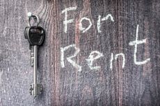 A bunch of keys hanging on a carnation on a wooden background, the inscription "for Rent