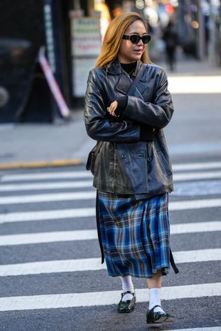 showgoer wearing plaid skirt, leather jacket, and black flats