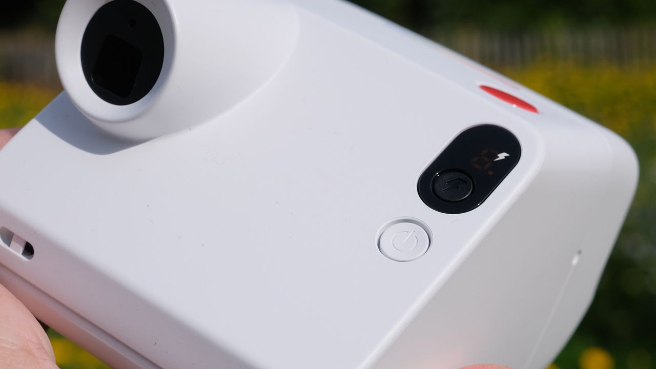Photograph of man's hand holding Polaroid Go Gen 3 camera in white