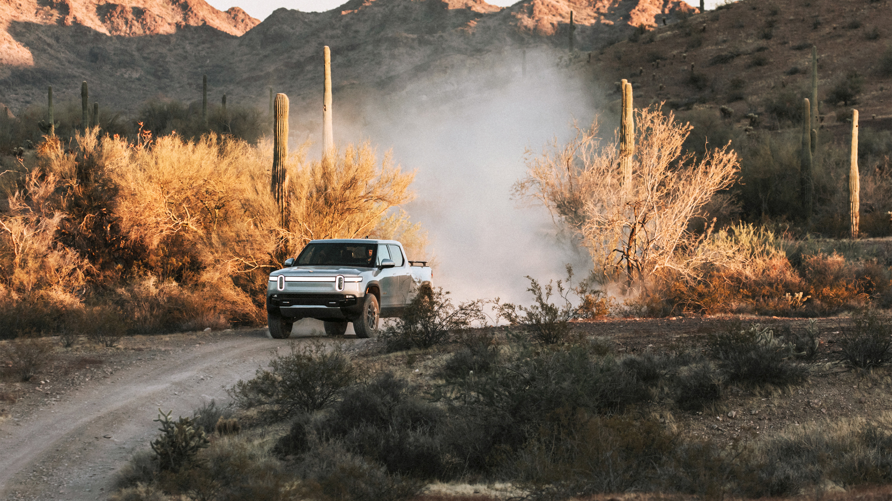 Rivian R1T drives through the countryside