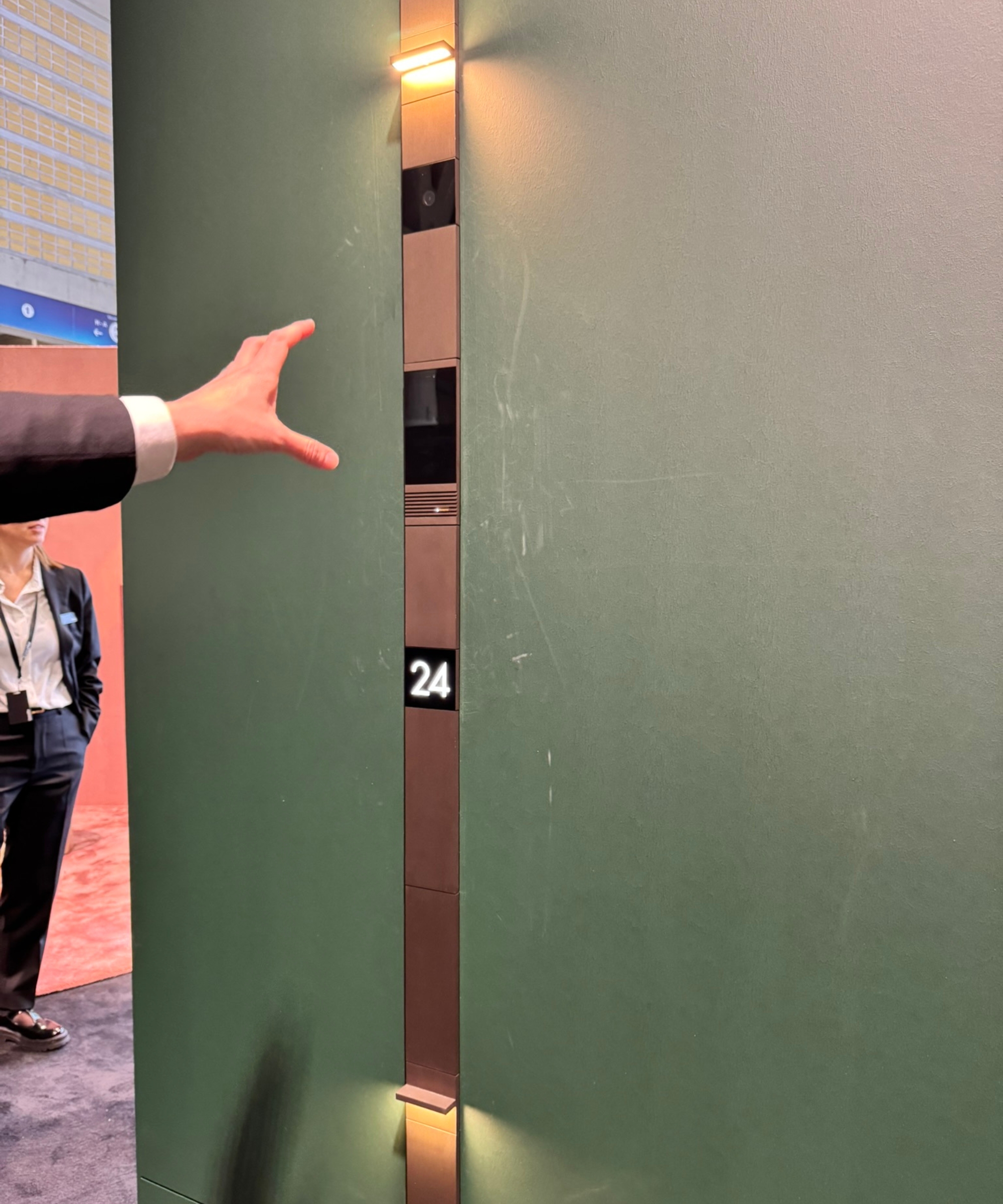 Basalte door phone in brass on green wall.